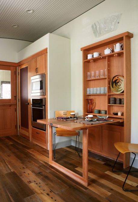 A dining space with storage and a wall monted table desk that cna be hidden any time