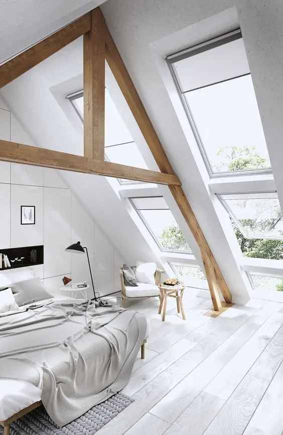 An off white attic bedroom with stained wooden beams and all neutral textiles and furniture