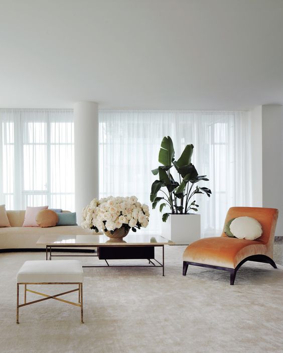 a peachy curved velvet lounger adds color and brings chic to the neutral space