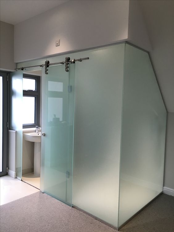 a bathroom cubicle clad with frosted glass and with a main sliding door is a bold idea for a modern space