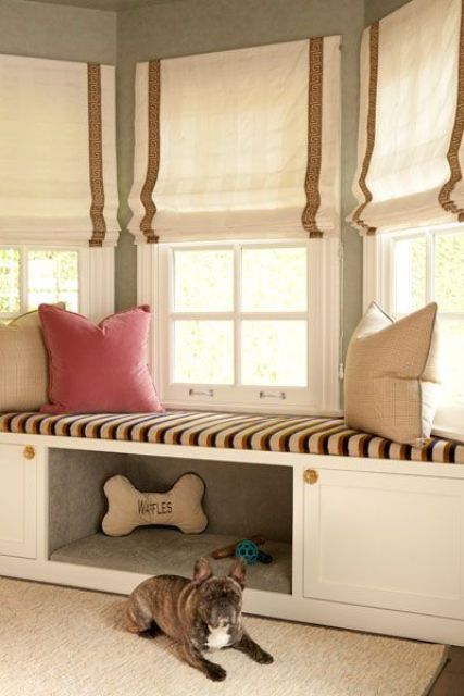 an upholstered windowsill bench with some built-in storage and a comfy pet niche with toys