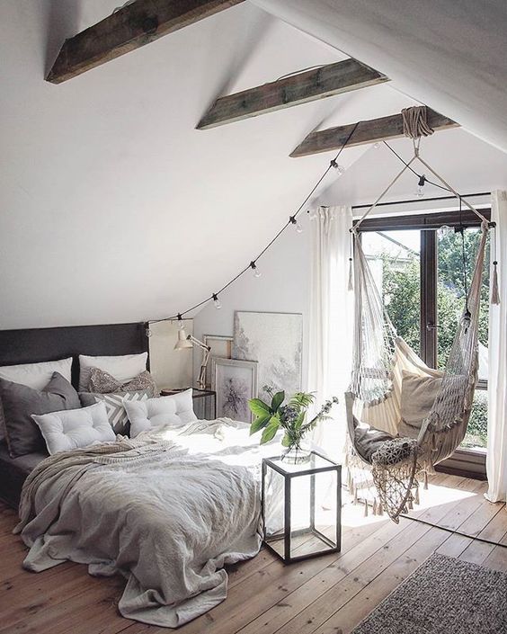 a cozy neutral bedroom with much light, stained beams on the ceiling and mcuh texture thanks to textiles