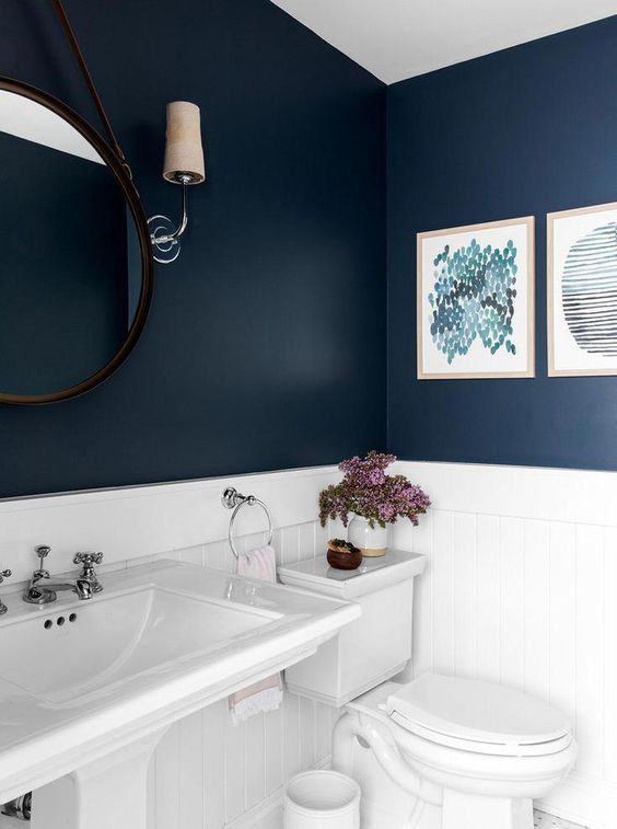 the bathroom features a contrasting look of a navy walls and white appliances and tiles