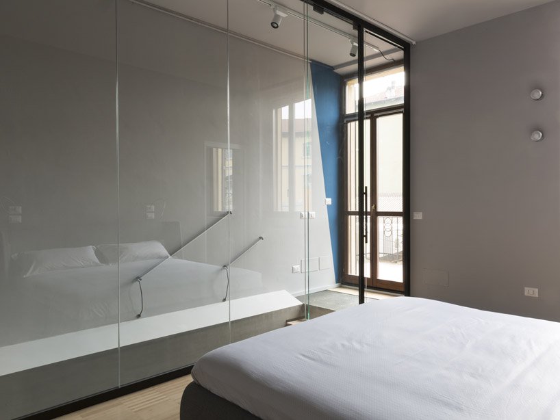 The bedroom is separated from the stairs with large sheets of glass