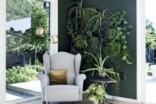 08 a dark green statement wall with lots of fresh potted plants and a little chair to make up a cozy nook
