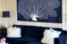 08 a nautical space with a navy tufted couch and a large artwork in navy and white showing off a coral