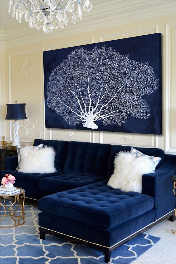 a nautical space with a navy tufted couch and a large artwork in navy and white showing off a coral