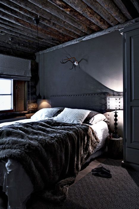 a welcoming dark cabin bedroom with a wooden ceiling and a faux fur throw plus wooden touches