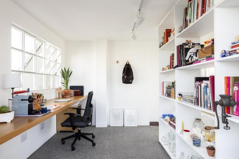 A home office is done with a large storage unit and a floating desk by the window, potted greenery refreshes the space