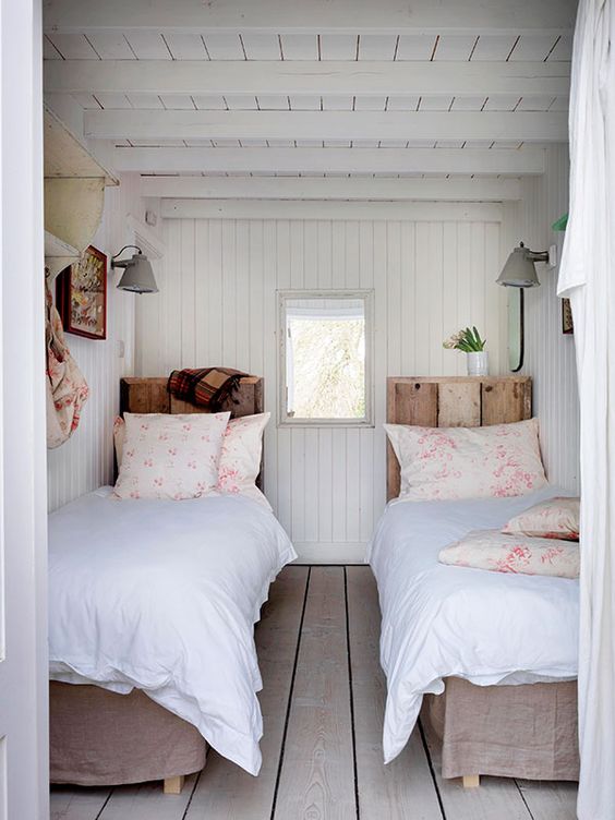 a cozy vintage-inspired guest bedroom with twin beds and wooden floors, walls and a ceiling