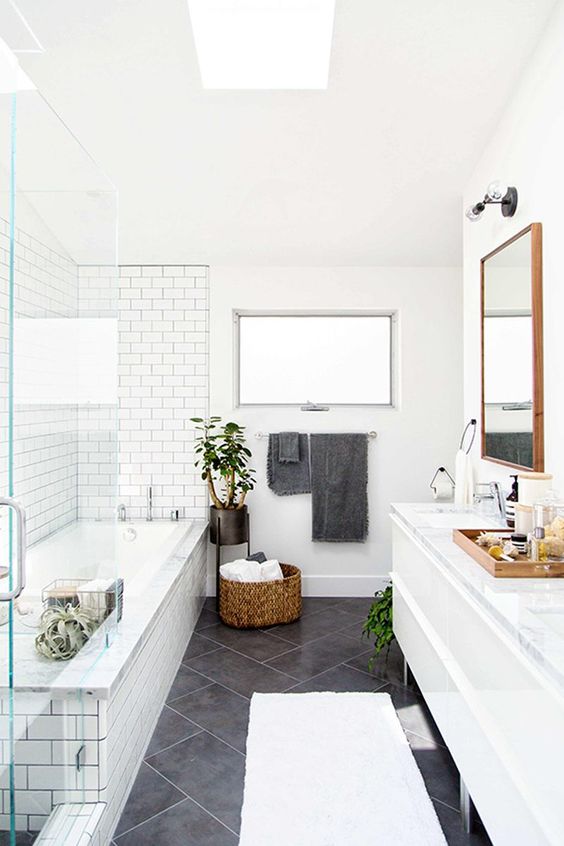 a neutral bathroom with white subway tiles and large grey tiles on the floor that stand out in these light shades