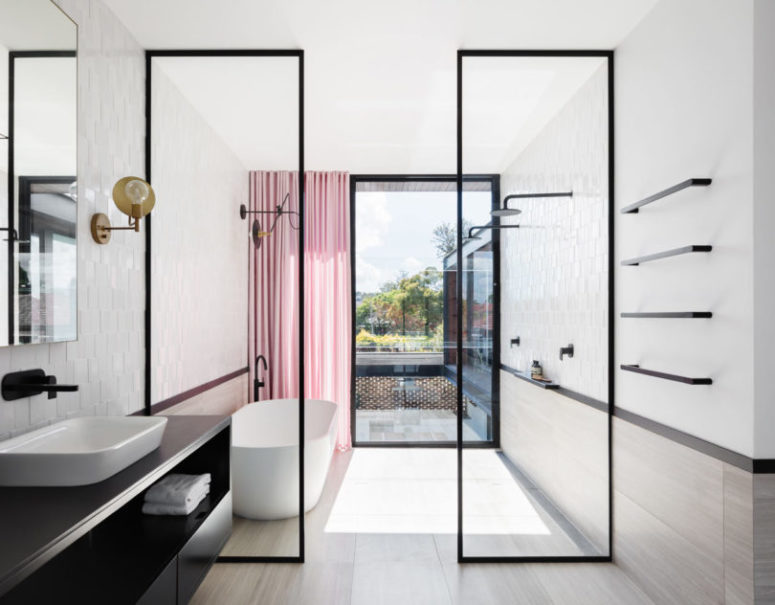 The bathroom is light-filled, airy and spacious accented with black touches and a pink curtain