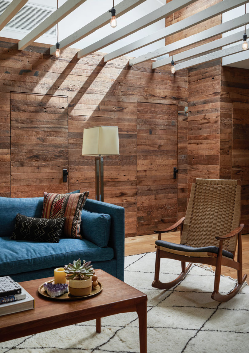 This space is done with weathered and rustic wood, there's a cool woven chair and a blue sofa