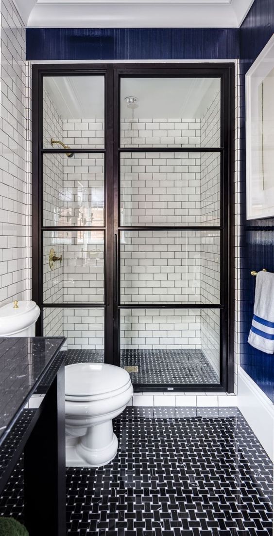 black and white graphic tiles on the floor, white subway tiles with black grout on the walls in a walk-in shower