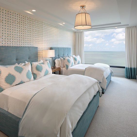 a fantastic guest bedroom with two large beds and a gorgeous panoramic sea view