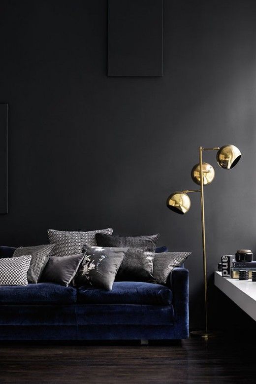 a chic moody living room with graphite grey walls, a navy sofa and an arrangement of various grey pillows