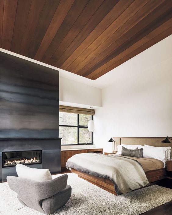 a fireplace completely covered with darkened metal is a gorgeous statement for a neutral bedroom