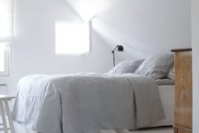 13 a fully white attic bedroom with touches of natural wood and some dark lamps