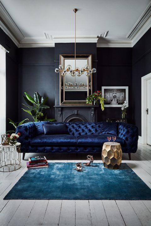 a fantastic and refined navy tufted velvet sofa adds a moody feel  and texture to the room