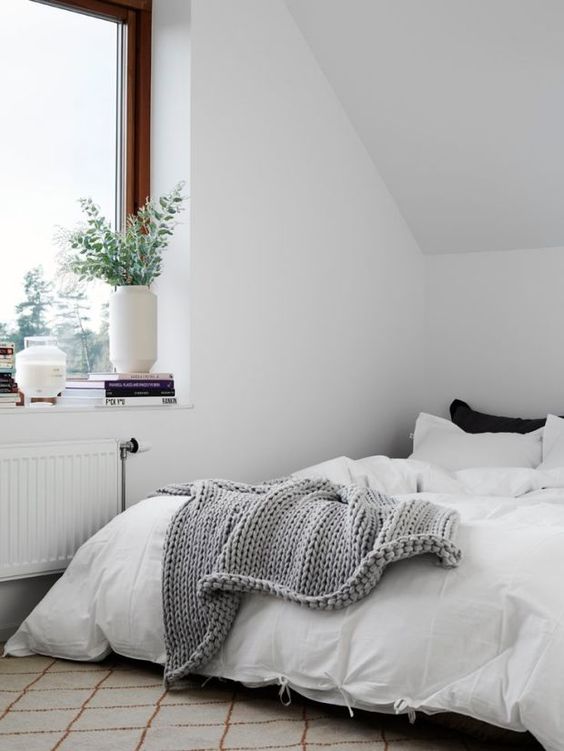 a minimalist attic bedroom done in mixed neutrals, with touches of black
