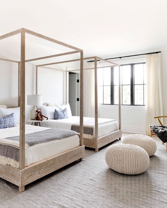 a modern beach twin guest bedroom with canopy beds, knit ottomans and much natural light