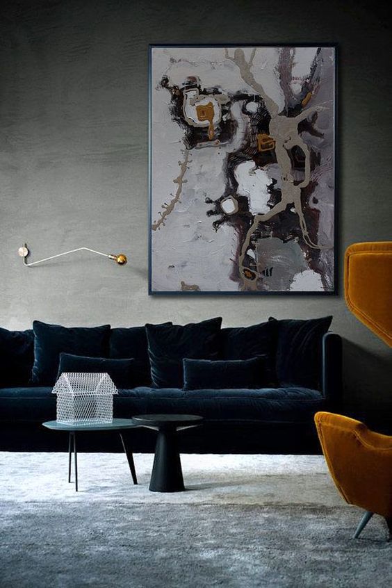 a sophisticated living room with grey walls and a floor, with a large refiend navy velvet sofa and pillows