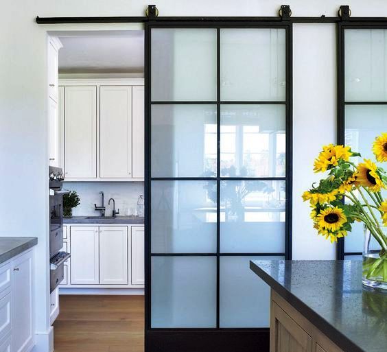 sliding doors with black framing and frosted glass divide the kitchen and the dining space very comfortably