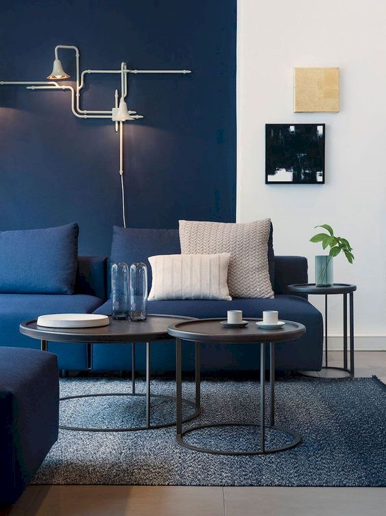a living room with a navy statement wall, a navy sofa and a grey rug plus coffee tables