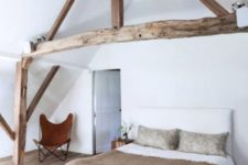 15 an attic space styled with only a comfy bed, a rustic bench and a leather butterfly chair
