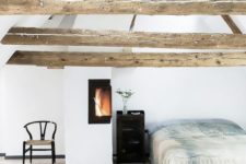 16 a cozy light-filled bedroom with wooden beams on the ceiling and a warming up hearth by the bed