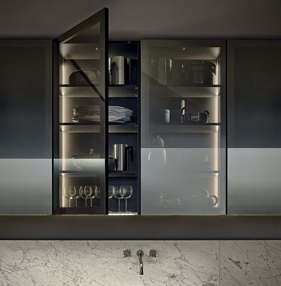 a kitchen cabinet with smoke glass doors shows off the glasses and dishes but does it gently