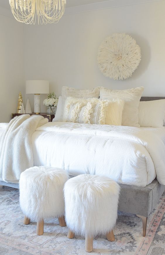 a cozying up printed rug, faux fur stools and fur throw blankets make the bedroom very inviting