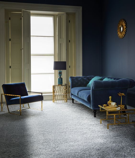 a refined living room with a grey floor, a navy wall, a navy sofa and chair