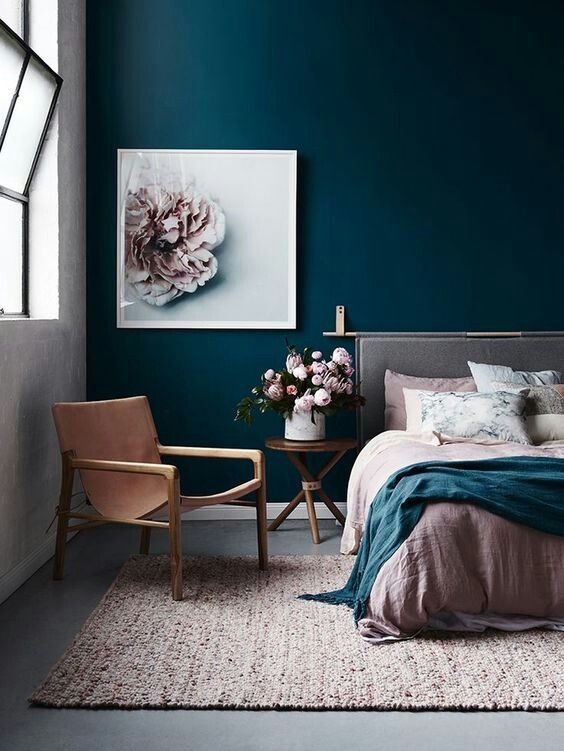 a chic bedroom done with a navy statement wall, a blush rug and bedding looks very inviting