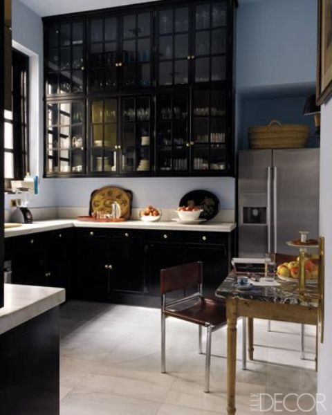 a refined kitchen with black cabinets and smoked glass upper cabinets plus white countertops for a contrast