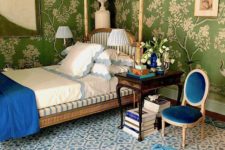 18 a sophisticated bedroom with botanical print wallpaper and medium blue accents – a chair, an ottoman and a blanket