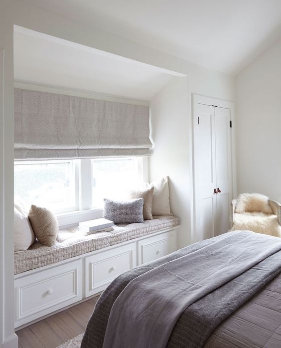 an upholstered window sill with storage is a stylish idea for a bedroom that doesn't have much space