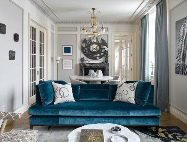a medium blue velvet sofa brings color to the space yet keeping it calm and relaxing enough
