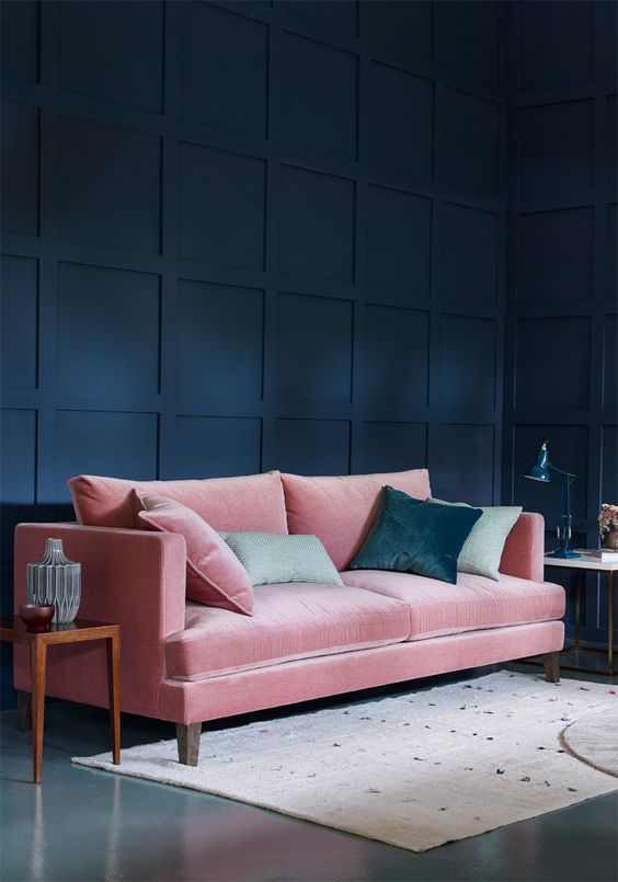 a refined living room with a navy statement wall and a pink velvet sofa plus green pillows