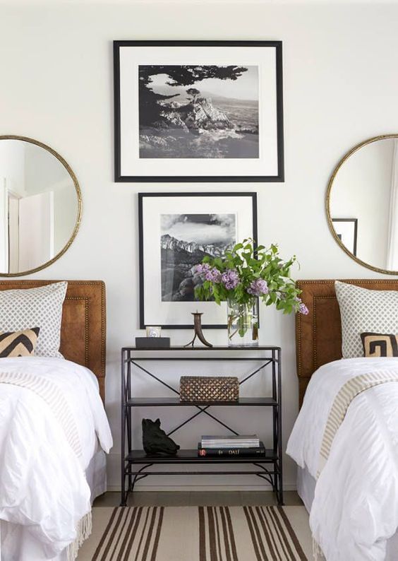 A stylish gender neutral guest bedroom with leather upholstered beds and round mirrors plus artworks