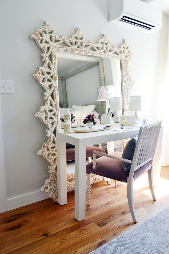 a chic vanity space with an oversized mirror and a purple velvet chair with curved legs