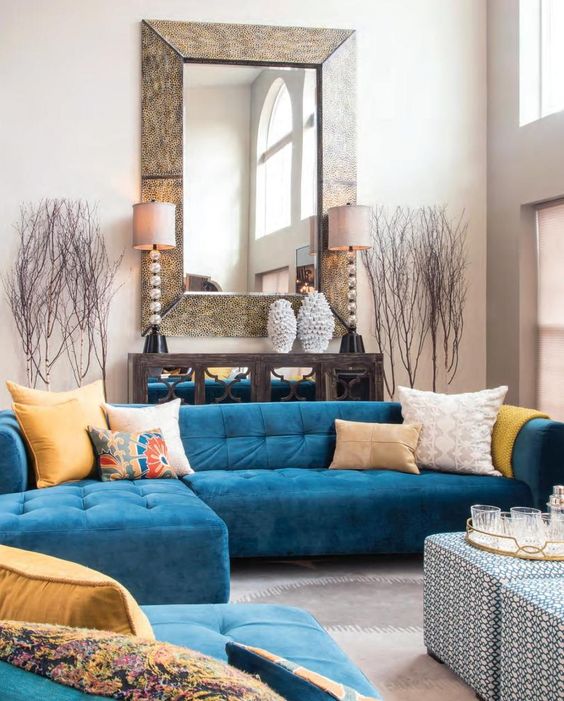 a gorgeous L-shaped medium blue sofa with sunny yellow pillows in a neutral interior