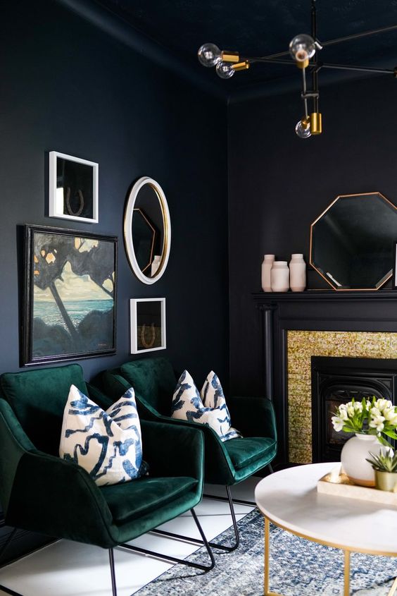 dark green velvet chairs in front of a black wall and brass touches for a chic look