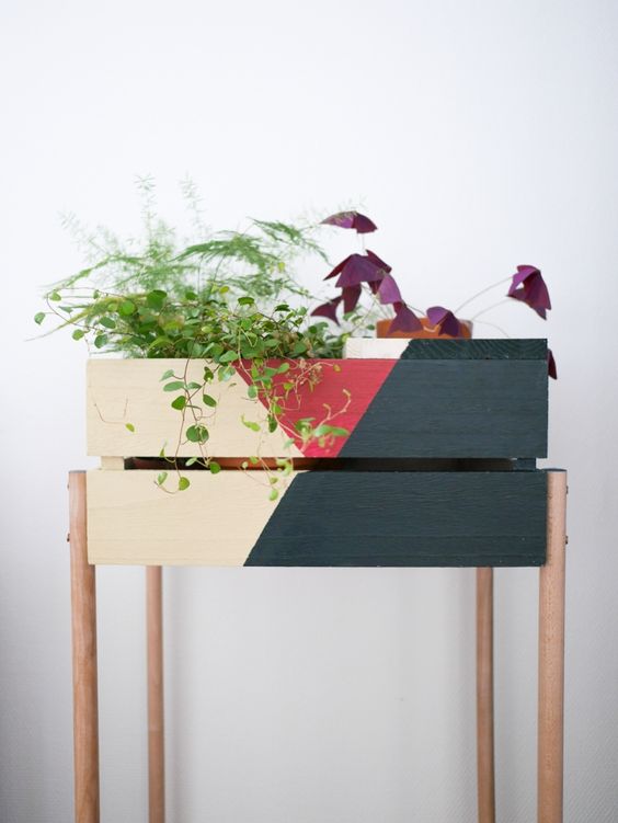 a color block Knagglig box placed on wooden legs can become a cool plant stand
