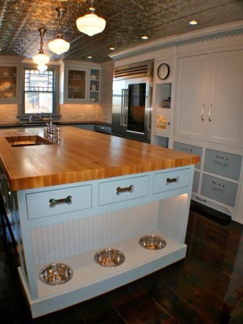 a kitchen island with an additional pet food station with lights and drawers for dog accessories