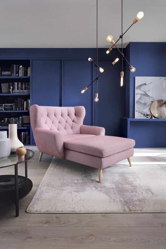 A mid century modern living room with navy walls and a blush lounger looks bold and fresh