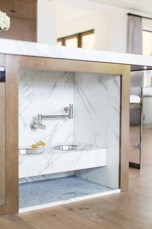 a kitchen island with an integrated pet food station done with marble contact paper is a stylish idea