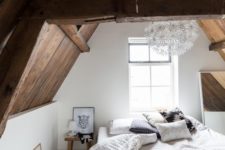 23 a large bed, a mirror and wooden bedside tables that echo with the sloped ceiling and beams