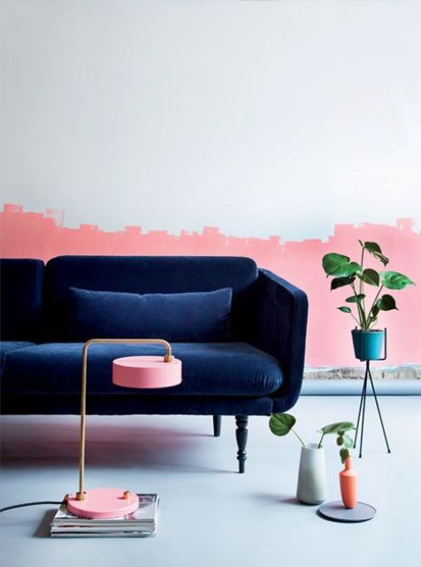 a living room with a catchy half pink wall and a refined navy velvet sofa