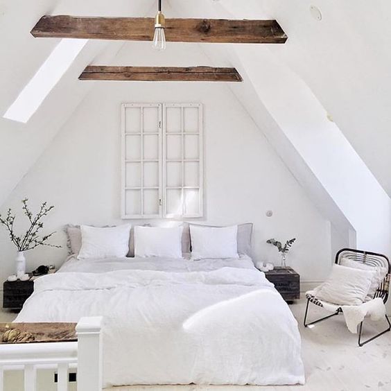 a very relaxing attic bedroom with a bed, bedside tables and a comfy chair by the window